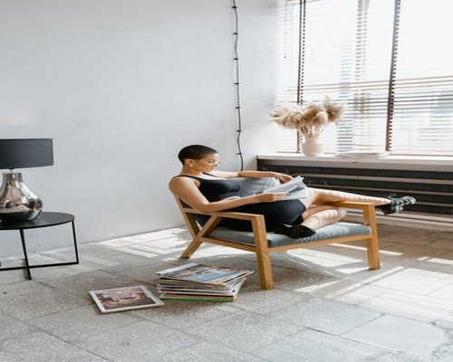 Person relaxing in a naturally lit room reading a magazine calmly