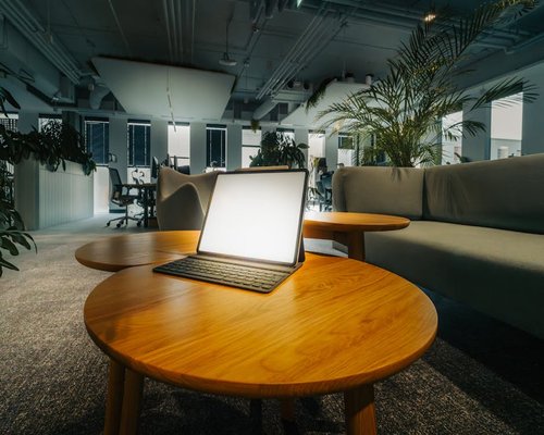 A tablet computer placed gently on an organic wooden surface under a warm yellowish desk light